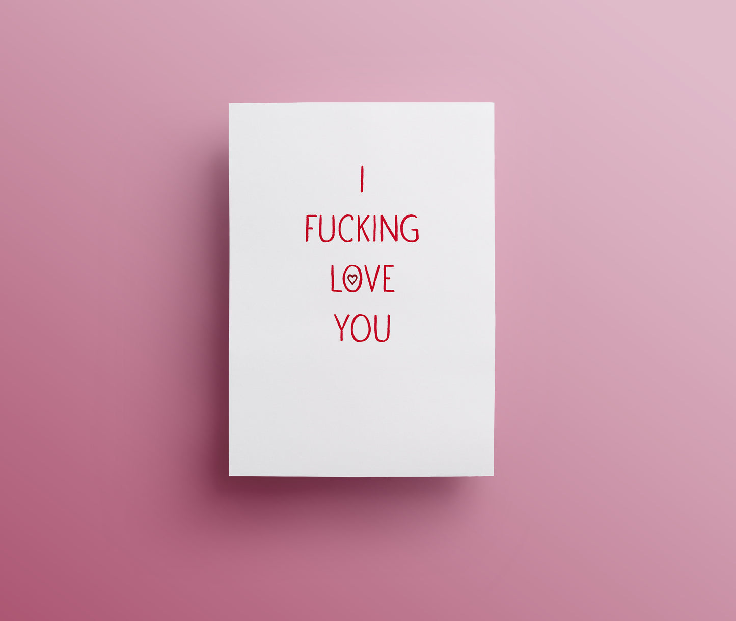 A white sweary rude greetings card with the text 'I FUCKING LOVE YOU' in red hand-drawn lettering, displayed against a pink background.