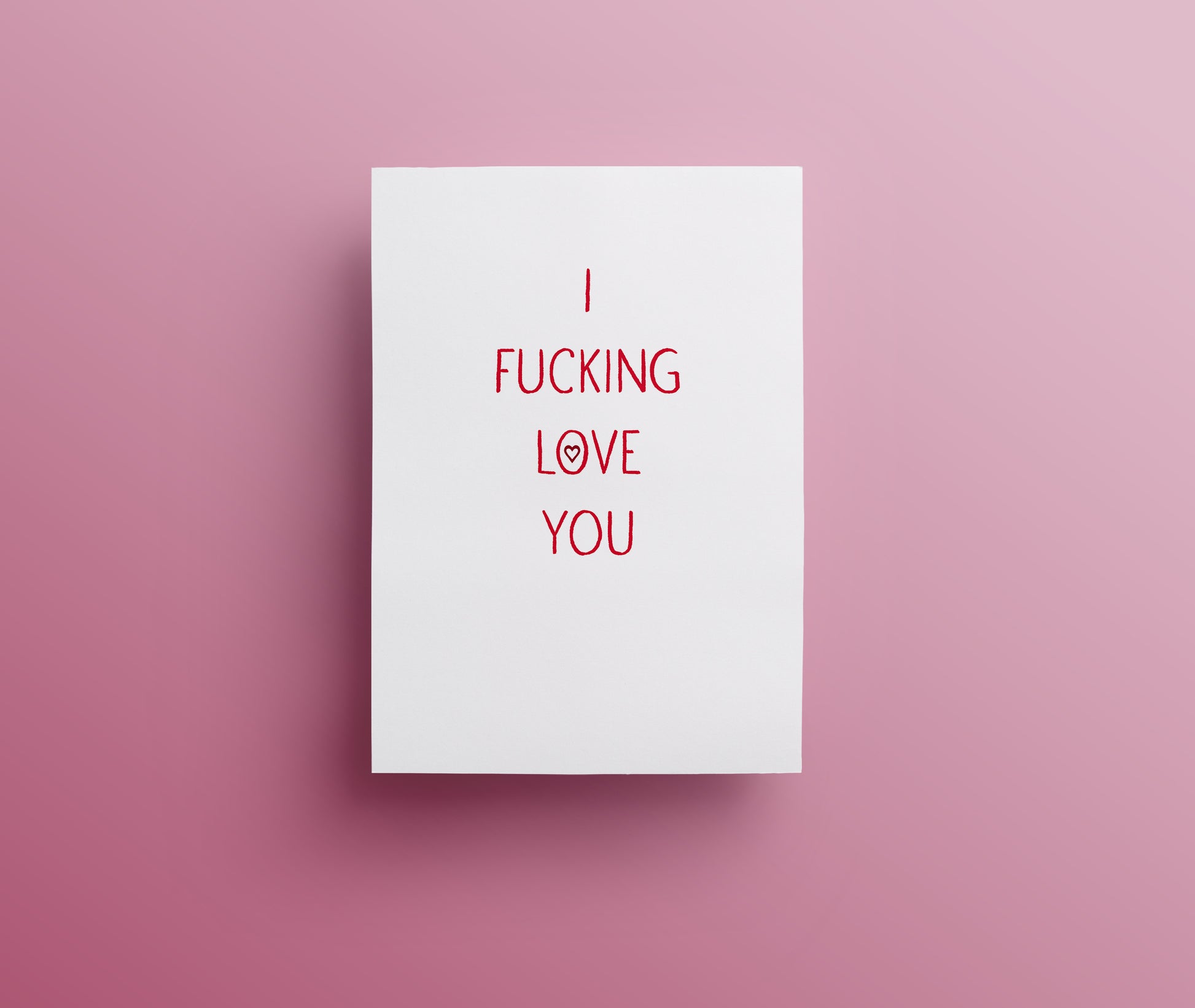 A white sweary rude greetings card with the text 'I FUCKING LOVE YOU' in red hand-drawn lettering, displayed against a pink background.