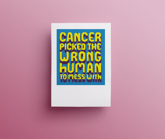 A blue greetings card with 'Cancer picked the wrong human to mess with' in bright yellow drop shadowed hand drawn lettering. 