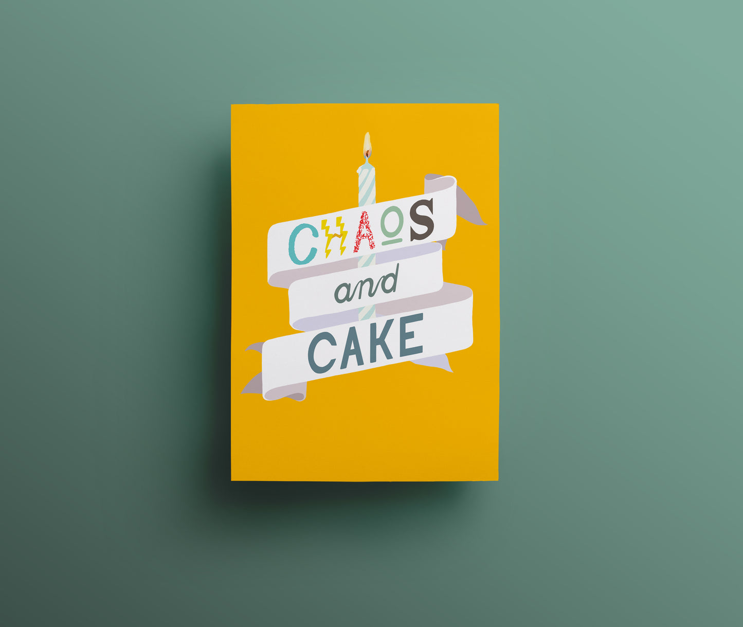 Yellow greetings card with a white banner and lit candle containing hand drawn lettering saying 'Chaos and Cake'.
